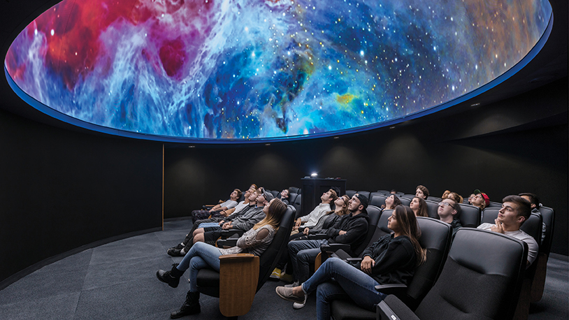 students looking up at the ceiling in the planetarium