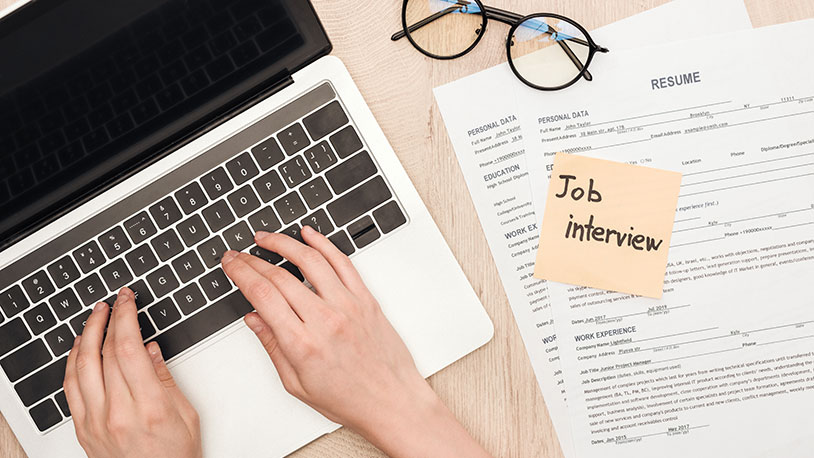 closeup of desk with computer and resume