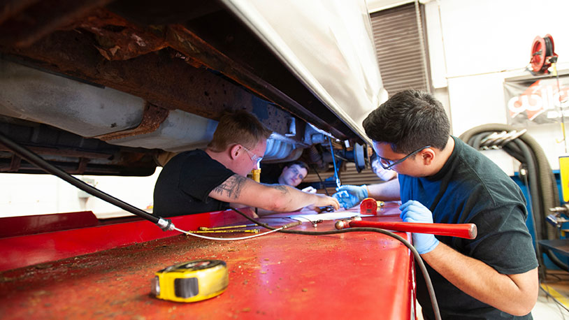 automotive students working under hood of car