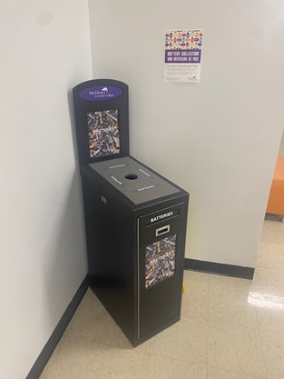 A recycling bin for batteries placed in the corner of a hallway