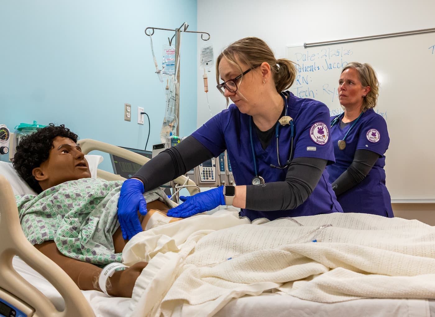 an MCC Nursing student applies a bandage to a patient simulator