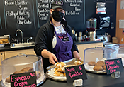 A student in chef's clothing presents baked goods