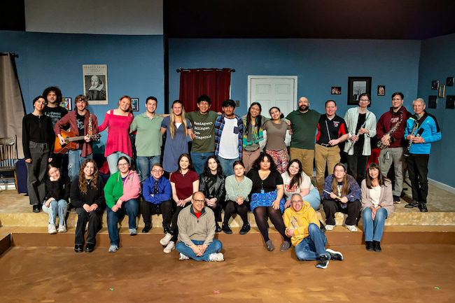 The cast and crew of I'm No Shakespeare stands in front the theatre in two rows