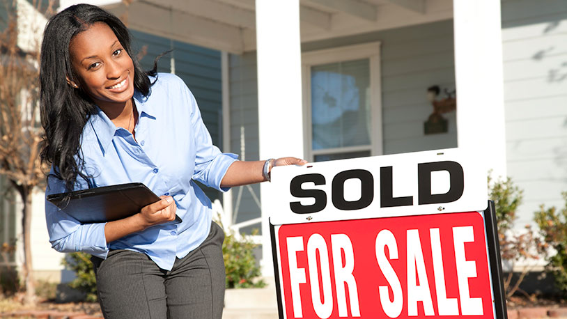 Realtor in front of house with sold sign