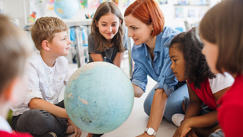 children in a classroom looking at a globe