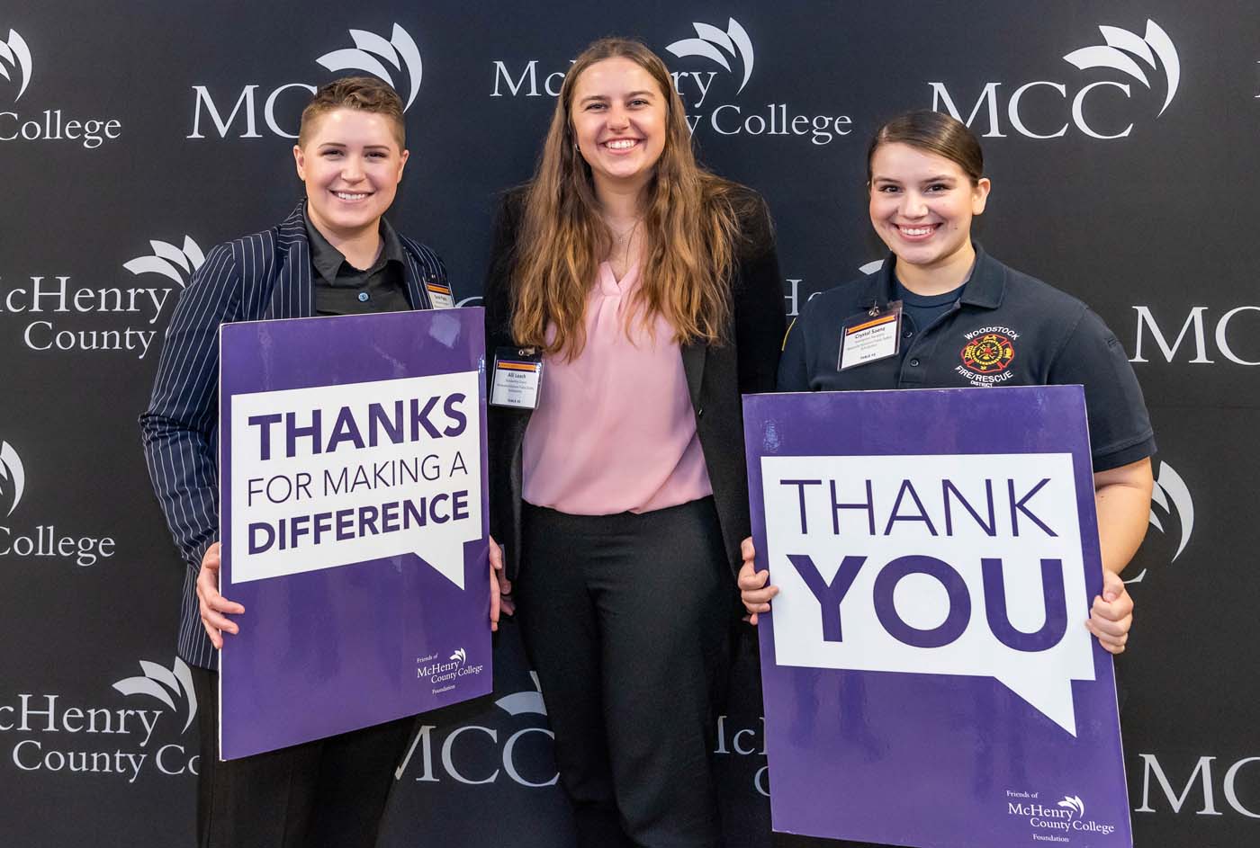 students hold thank you signs for receiving MCC scholarships