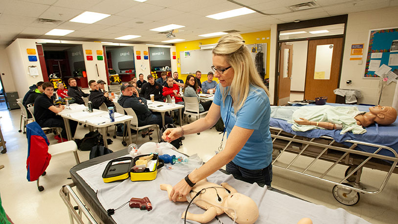 instructor demonstrating for ems students in emergency treatment on training baby