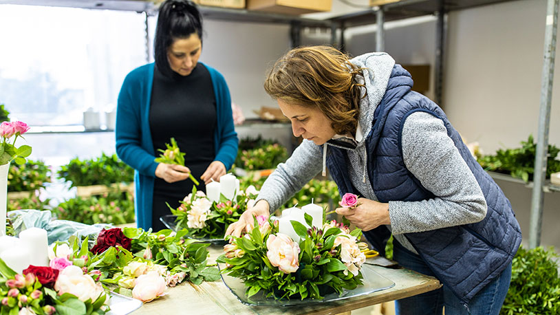 two floral designers in shop designing floral arrangements