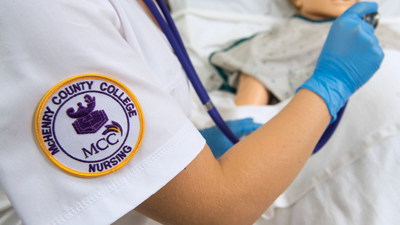 closeup of an MCC nursing patch on the arm of the scrubs seen on a White student's arm