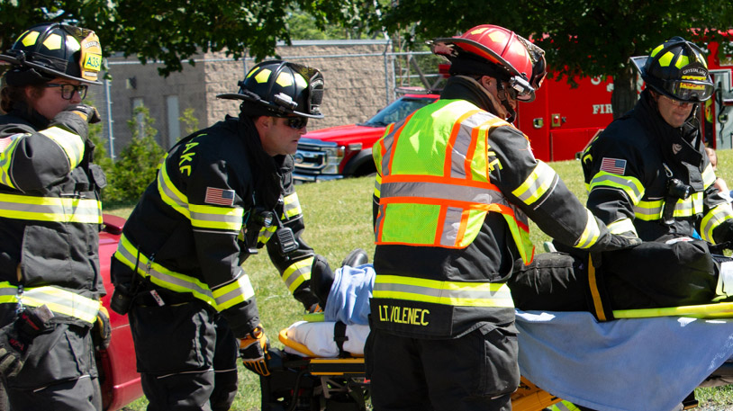 Firefighters in full gear are carefully transporting an injured person on a stretcher during an emergency response.