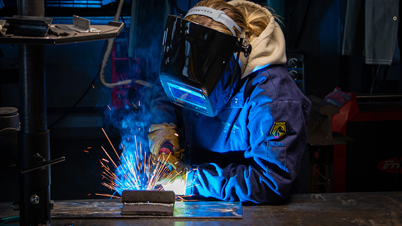 Welding student in class wearing welding helmet