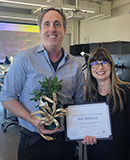 Bob Mihelich: 2026 Faculty Member of the Year is holding a small potted plant. He is standing next to Daniela Broderick, who is holding his certificate of recognition.
