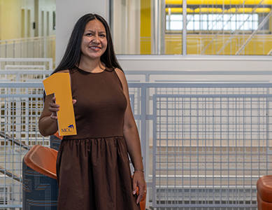MCC student Martha Malvaez stands in the CATI holding a number 1. 