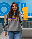MCC student Yadira Placencia, wearing a gray MCC 1967 sweatshirt, holds a yellow number 1 cutout in Co/Lab B.
